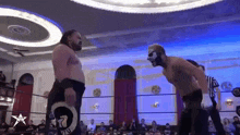 two men are wrestling in a ring with a referee .