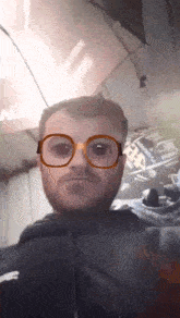 a man wearing glasses is making a funny face in front of a sign that says ' alpha '