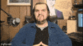 a man in front of a microphone with a picture of a man on the wall behind him and the words imgflip.com