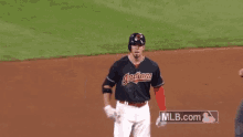 a baseball player wearing a cleveland indians jersey is standing on the field with a referee .