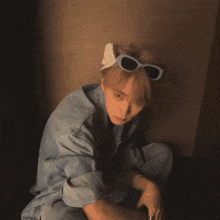 a young man wearing a denim jacket and sunglasses looks at the camera