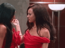 two women in red dresses are looking at each other .