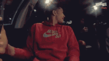a man in a red nike hoodie is smoking a cigarette in a car