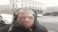 a man wearing headphones is standing in front of a building on a street .