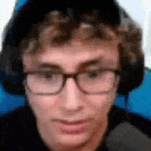 a young man wearing glasses and headphones is looking at the camera .