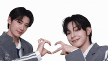 two boys are making a heart shape with their hands .