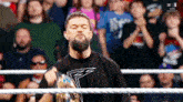 a man with a beard is in a wrestling ring holding a trophy .