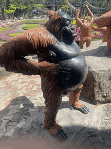 a statue of an orangutan with a large belly is standing on a rock