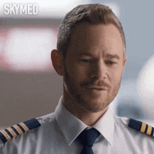 a man with a beard is wearing a white shirt and tie and the word skymed is behind him