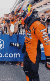 a man wearing a helmet stands in front of a banner that says o.com