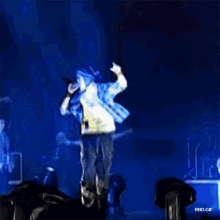 a man in a plaid shirt is singing into a microphone