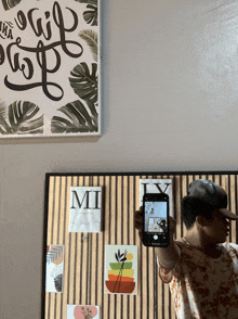 a man is taking a picture of a wall with a sign that says " mi "