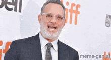 a man with a beard wearing glasses and a suit stands in front of a sign that says tiff