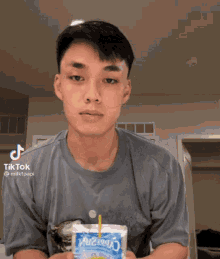 a young man is holding a packet of rice milk