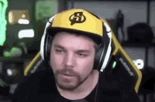 a man with a beard is wearing headphones and a hat while playing a video game .