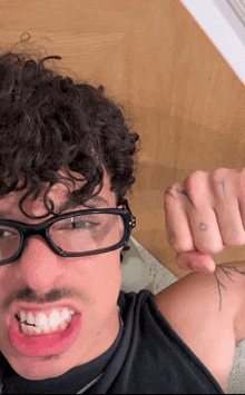a man with curly hair wearing glasses and a black shirt