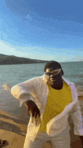 a man wearing sunglasses and a yellow shirt is standing on a beach .