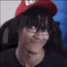 a man wearing a red hat and glasses is smiling .