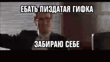 a man in a suit and tie is standing in front of a window with a sign in russian .