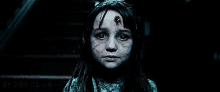 a close up of a scary girl with blood on her face screaming .