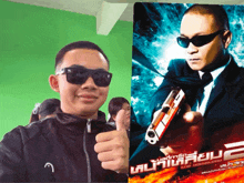 a man wearing sunglasses giving a thumbs up next to a poster for a movie