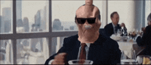 a man wearing sunglasses is sitting at a table with a plate of food in front of him