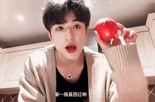 a young man is holding a tomato with chinese writing on the bottom