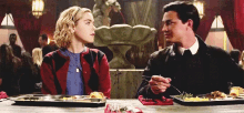 a man and a woman are sitting at a table with trays of food .