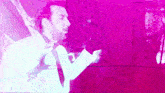 a man in a white shirt and tie is dancing in front of a pink background