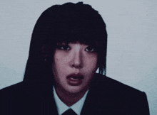 a woman in a suit and tie looks at the camera with a serious look on her face