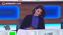 a woman is sitting at a table with a sign that says ' j.me ' on it