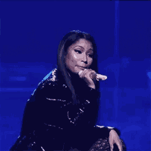 a woman is singing into a microphone while sitting on a stage .
