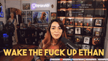 a woman stands in front of a microphone with the words wake the fuck up ethan above her