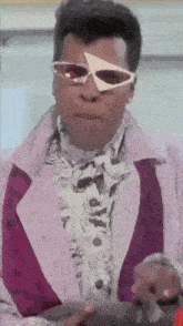 a man wearing sunglasses and a purple jacket has a triangle on his forehead