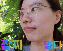 a woman wearing glasses and a nose ring is surrounded by colorful letters in korean