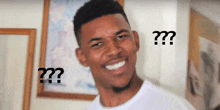 a man is smiling and looking at the camera with two question marks above his head