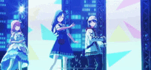 three anime girls are dancing on a stage in front of a large screen