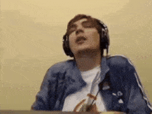 a man wearing headphones and a blue jacket is singing into a microphone .