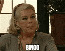 a woman is sitting in front of a window and the word bingo is on her face .