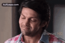 a man in a plaid shirt is smiling with his eyes closed and his mouth open .