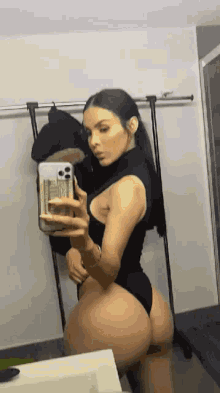 a woman is taking a selfie in front of a mirror with her phone .