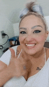 a woman with a tattoo on her chest is smiling and giving the thumbs up