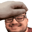 a man wearing glasses and a hat is smiling and holding a stuffed animal on his head .