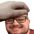 a man wearing glasses and a hat is smiling and holding a stuffed animal on his head .