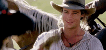 a man in a cowboy hat is smiling while riding a horse .