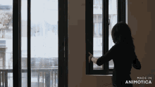 a woman is looking out a window with the words made in animotica on the bottom