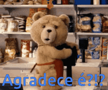 a teddy bear in an apron is hugging another teddy bear in front of a sign that says agradece e