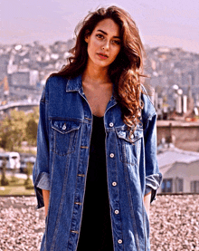 a woman wearing a long denim jacket with buttons on the front