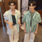 two men standing next to each other wearing green striped shirts