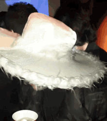 a person is holding a large white feathered object